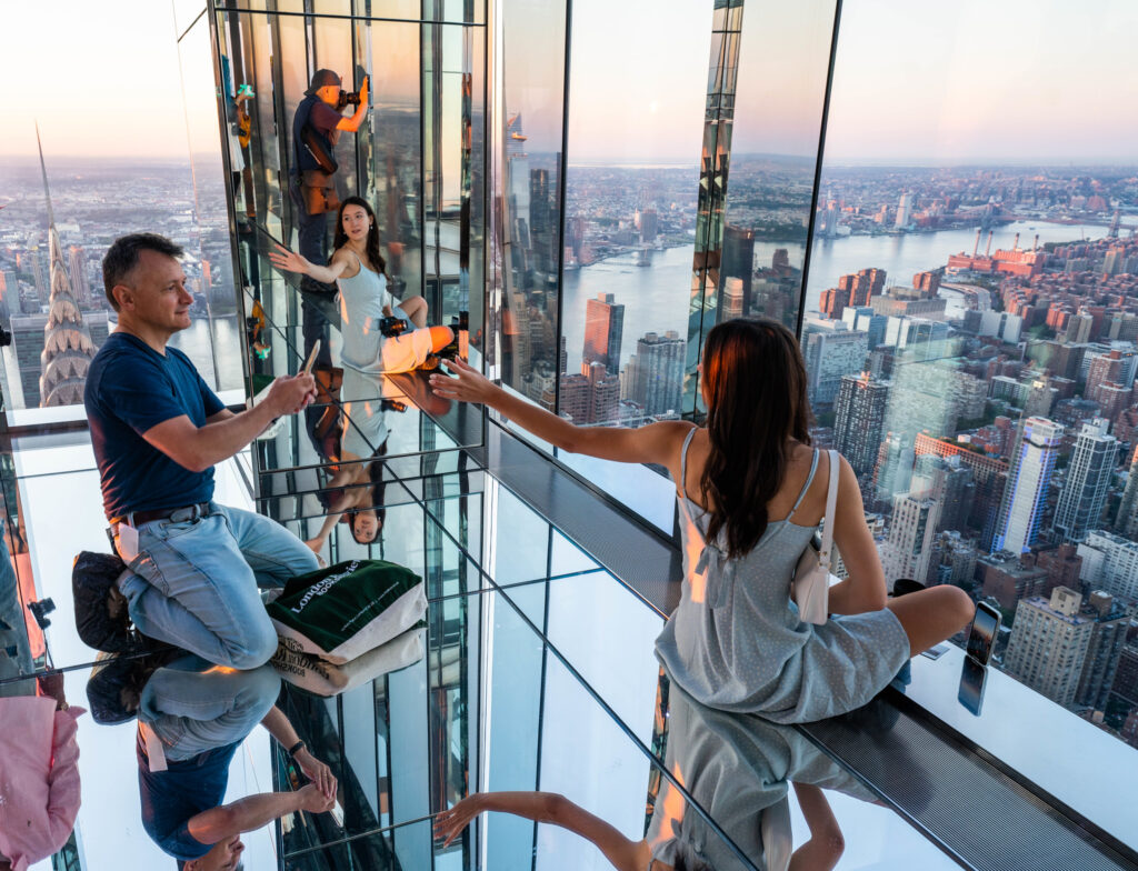 Мужчина фотографирует девушку на смотровой площадке Саммит Вандербит (SUMMIT One Vanderbilt) в Нью-Йорке.